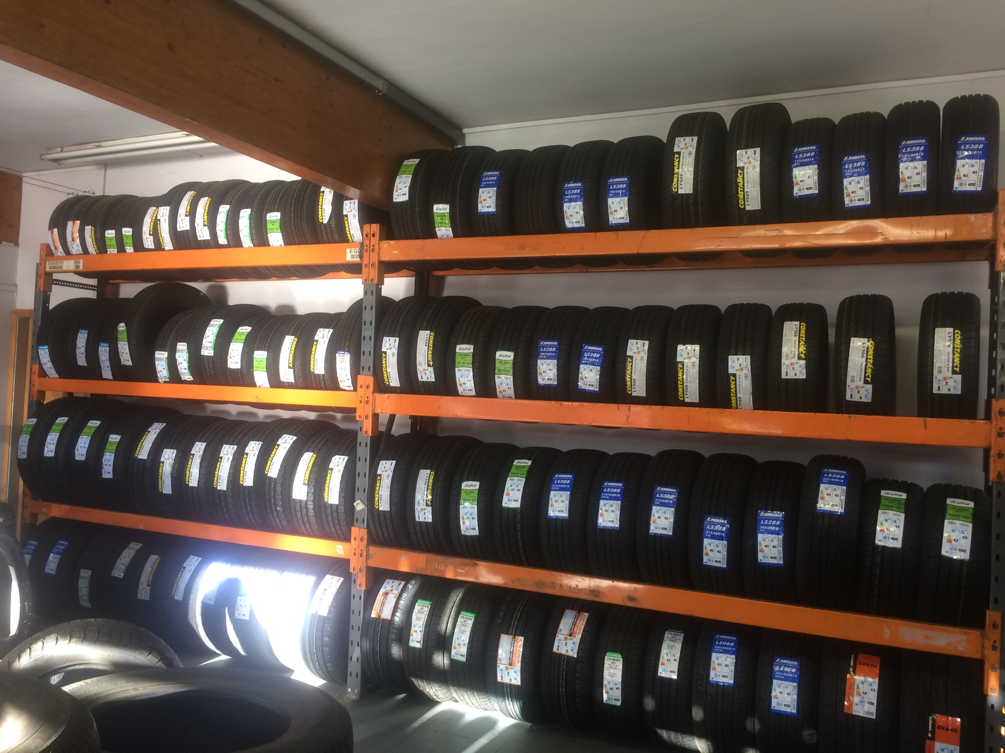 Orange racking stacked floor to ceiling with new tyres in the Rushden Tyres shop