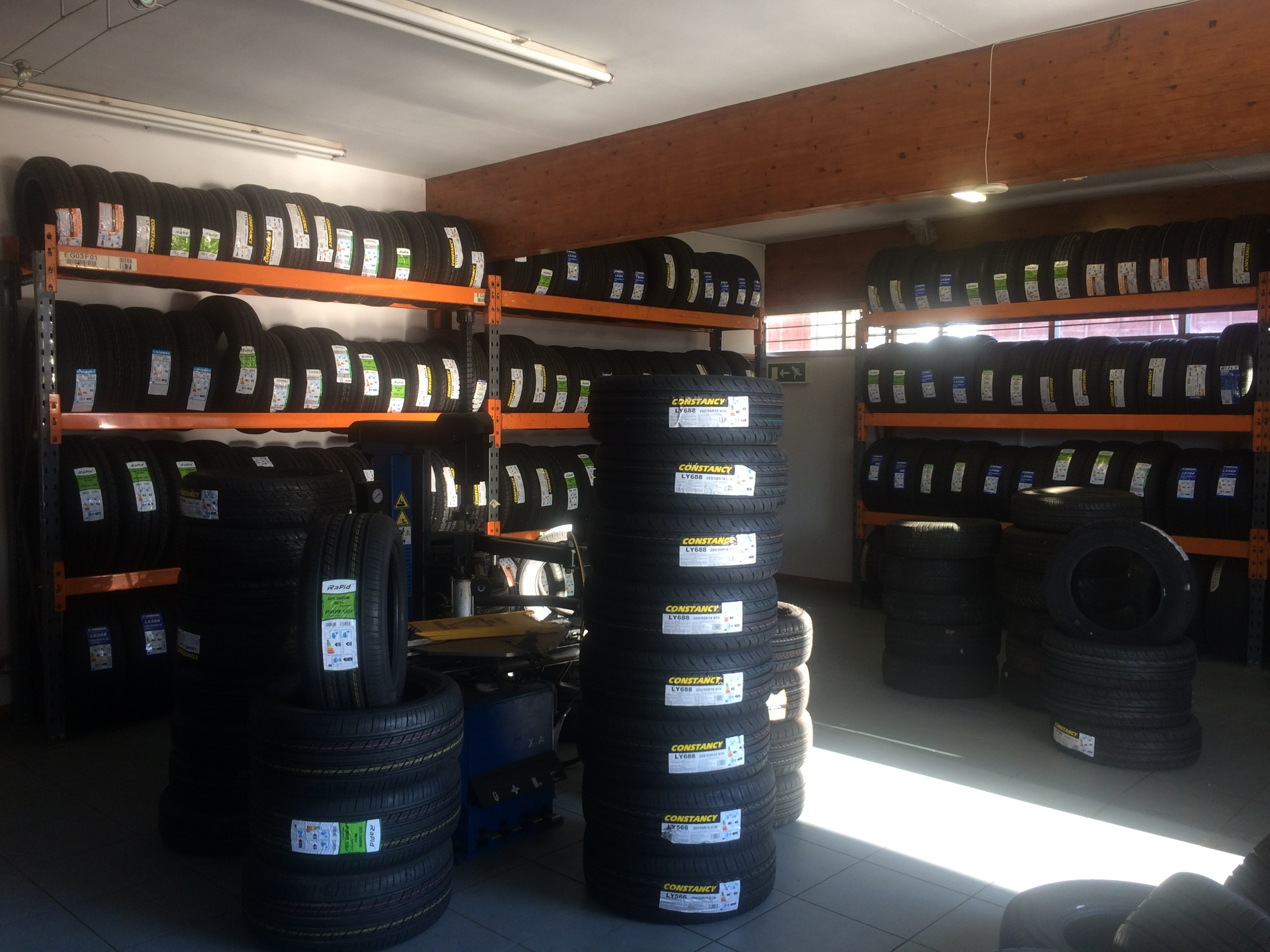 Racks and tall stacks of new tyres inside the Rushden Tyres workshop