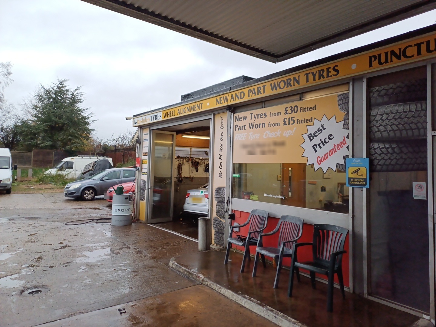 The Rushden Tyres bay on a wet day, a car on the lift and chairs outside the window